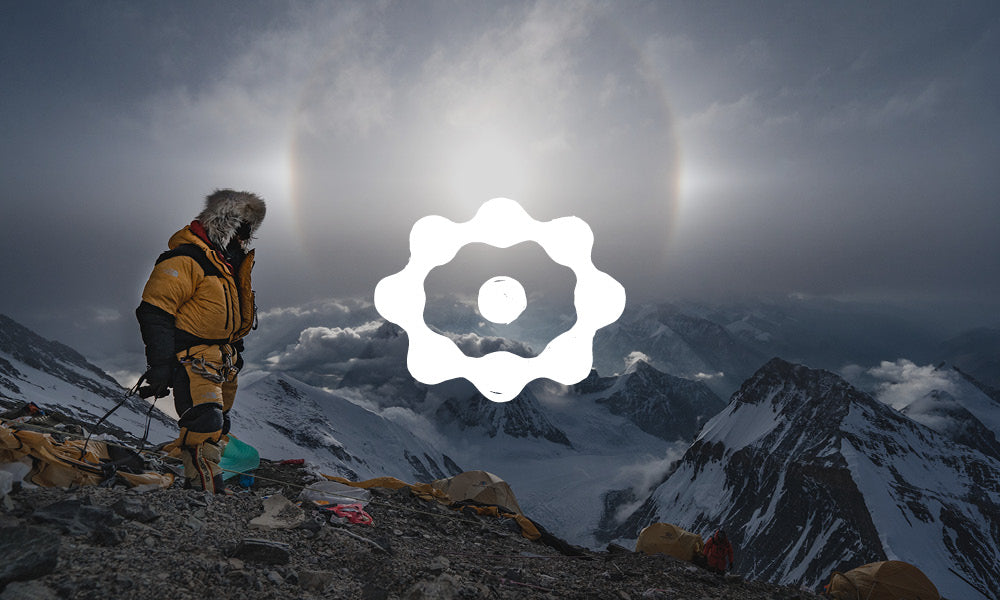 Photo of a mountain climber at the top of a snowy peak, carrying climbing gear. There is an icon on top of the image.