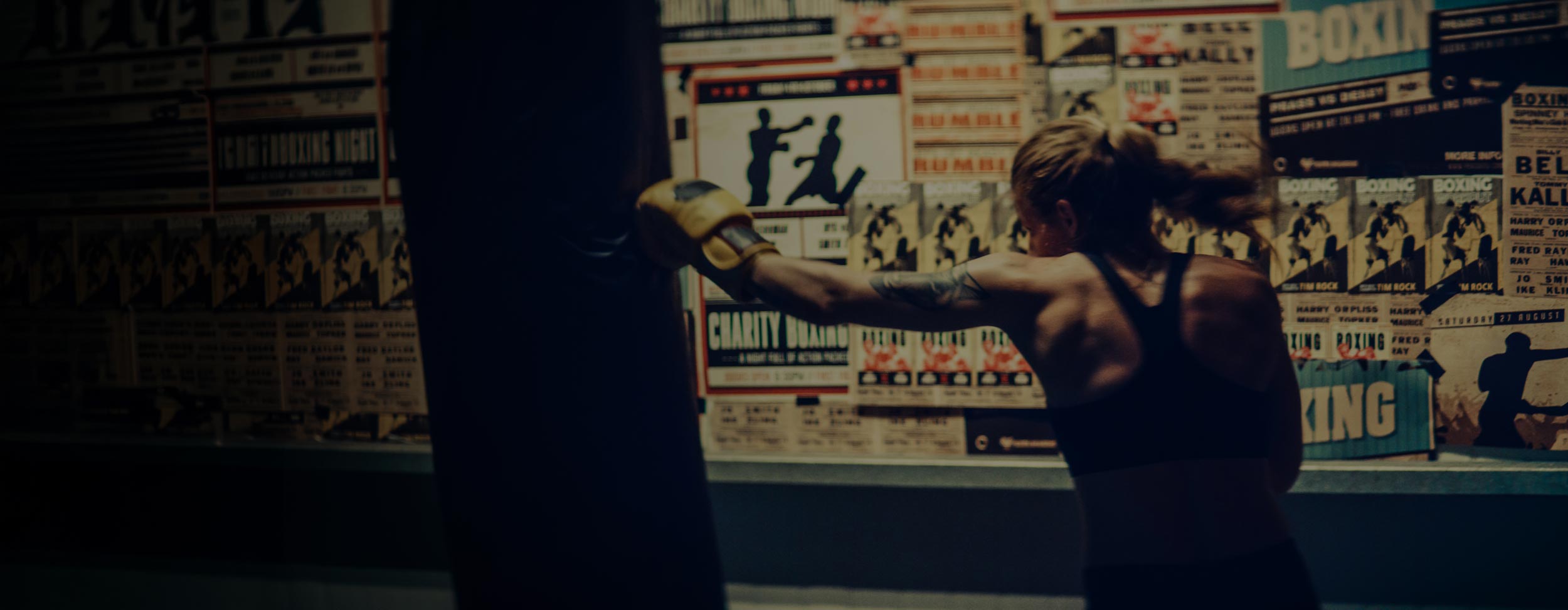 Person practicing boxing in a room with boxing posters on the wall