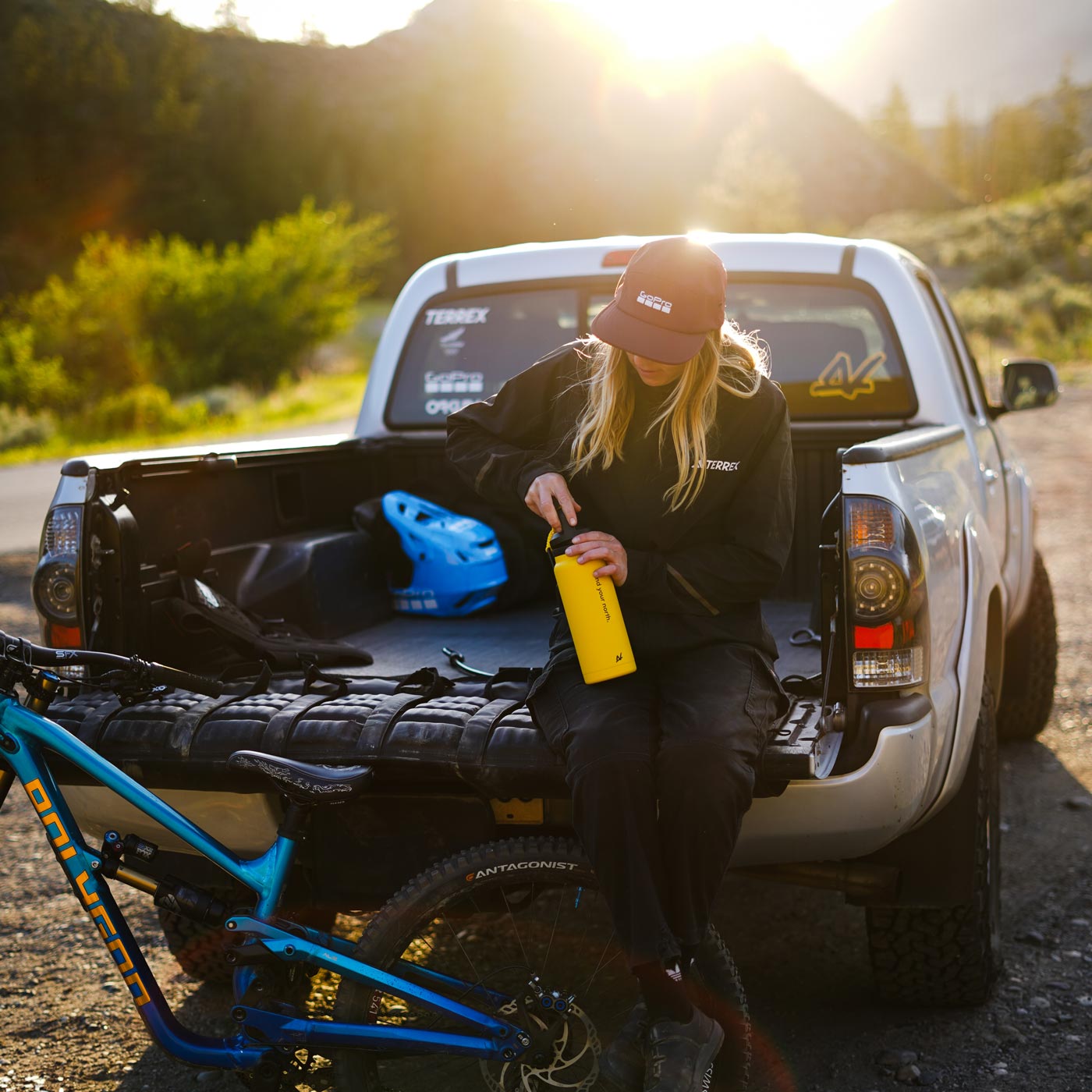 Photo of athlete Dominique Ohaco sitting on the bed of her truck, holding a NORTH Performance water bottle.
